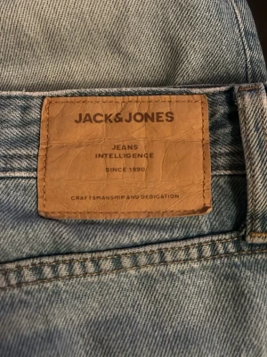 Ljusblå jeans från Jack & Jones - Snygga ljusblå jeans från Jack & Jones med klassisk femficksmodell och knäppning med fyra knappar. Jeansen är i denim och har en avslappnad passform, perfekta till din vardagsstil.