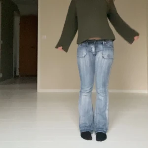 lågmidjade Ljusblå bootcut jeans  - Säljer ett par ljusblå bootcut jeans med snygga slitningar och dekorativa sömmar på bakfickorna. Jeansen har låg midja och klassisk femficksdesign. midjemåttet är 38cm, Innerbenslängden är 76cm och grenmåttet är 17cm! skriv för frågor, pris kan diskuteras💕💕