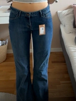 Blå bootcut jeans från lindex - Säljer ett par blå bootcut jeans från Uniqlo med klassisk femficksmodell och normal midja. Jeansen har en snygg utsvängd passform nertill och är tillverkade i denim med lätt stretch. Perfekta för en trendig och avslappnad look.