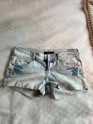 Ljusblå denimshorts från Tally Weijl  - Säljer ett par ljusblå denimshorts från Tally weijl med klassisk femficksdesign och dubbla knappar framtill. Shortsen har uppvikta benslut. Perfekta för sommaren. 