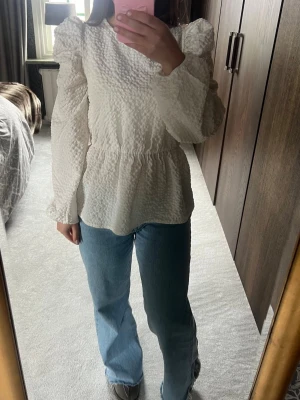 Vit strukturerad blus med puffärm - Supersnygg vit blus med strukturerat tyg och voluminösa puffärmar. Rund halsringning och markerad midja som ger en feminin siluett. Köpt för 600kr 