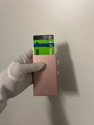 Rosa korthållare i metall + RFID skydd - Snygg och smidig korthållare i metall från Cosmos Sweden. Svensk märke. Matt rosa färg. Perfekt för dig som vill ha koll på dina kort utan att bära runt på en stor plånbok. Modern och minimalistisk design med knapp för att skjuta upp korten.