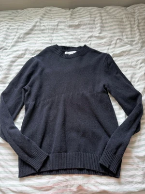 Mörkblå stickad tröja unisex - En stilren mörkblå stickad tröja med rund halsringning och ribbade muddar vid ärmslut och nederkant. Tröjan har en klassisk passform och är perfekt för lager-på-lager. Materialet känns mjukt och passar till många olika outfits. Använd men bra skick! Från dressman. Diskuterar gärna pris:) Storlek runt M-L