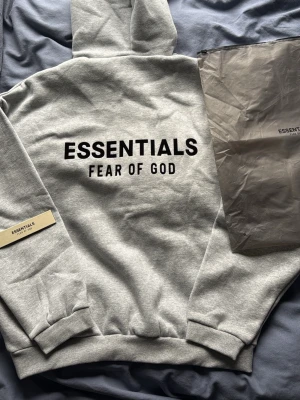 Grå Essentials Hoodie - Snygg Essentials Fear of god hoodie i grå färg. Storlek S. Skicka gärna ett bud vid intresse. Längd: 66cm Bredd:64cm. Fraktas inom 24h☺️📦