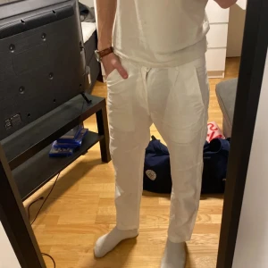 Vita linnebyxor med dragsko - Snygga vita linnebyxor med avslappnad passform och dragsko i midjan. Byxorna har sidofickor och är tillverkade i ett lätt och luftigt linnematerial, perfekta för en chill och stilren look.