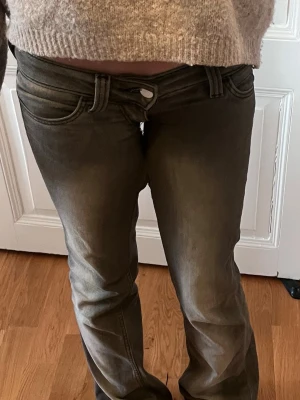 Grå bootcut jeans med slitningar - Väldigt lågmidjade från weekday. Ett litet hål men går att laga för hand Säljer ett par grå bootcut jeans med snygga slitningar och tvättade detaljer. Jeansen har klassisk femficksmodell, låg midja och vida ben. Perfekta för en avslappnad och trendig look.