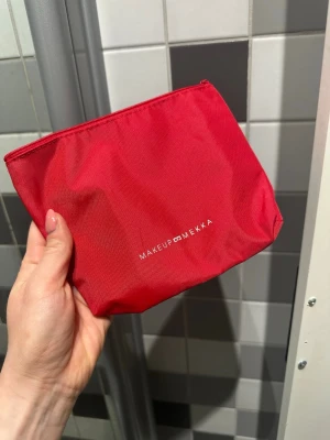 Röd necessär från Makeup Mekka - Snygg röd necessär från Makeup Mekka i slitstarkt tygmaterial. Perfekt för att förvara smink, borstar eller andra skönhetsprylar. Stängs med dragkedja och har en stilren design med logga framtill.