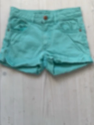 Turkosa shorts med fickor - Snygga turkosa shorts med uppvikta ben och klassisk femficksdesign. Shortsen har bälteshällor och knappstängning framtill. Perfekta för varma dagar och ger en fräsch look. Är från H&M och är 134.