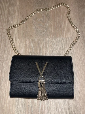 Väska - Väska från Valentino köpt på zalando (2024) online, kvitto på leverans finns då den köptes, svart med silver, köptes för 669kr (axelremsväska) den är liten, har dock inte kvar påsen eller förpackning till den! Självklart ÄKTA!!!⭐️ Har dock lite fläckar men inte jätte synliga, den är fin och ren! 