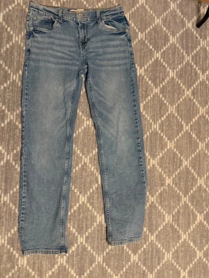 Levi's ljusblå raka jeans - Ljusblå jeans från Levi's med klassisk femficksdesign och raka ben. Jeansen har ochså den ikoniska Levi's-lappen på bakfickan. Materialet är denim och passformen är rak. Perfekt för dig som gillar en tidlös och avslappnad look. Storlek 14a som kanske är 29 30