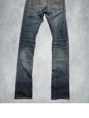 Blå jeans från Nudie Jeans - Säljer ett par blå jeans från Nudie Jeans med klassisk femficksdesign och snygga slitningar. De har små slitningar där fram som sitter snyggt. Om man vill ha bättre bild kan man höra av sig. De är längre men jag vek dem på bilderna så de inte såg så långa ut. Jag är 157cm lång.