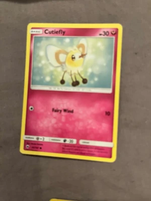 Pokémonkort Cutiefly - Säljer ett Pokémonkort med Cutiefly-motiv. Kortet har en gul ram, rosa bakgrund och visar den söta Pokémonen Cutiefly. Materialet är klassiskt glansigt papp som används till samlarkort. Perfekt för dig som gillar att samla eller spela Pokémon TCG.