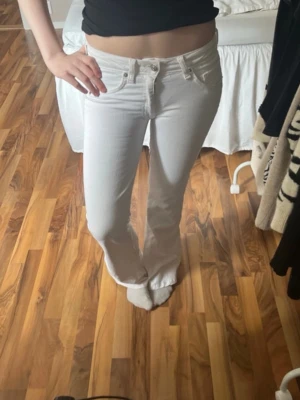 Vita bootcut jeans med medelhög midja  - Säljer ett par vita bootcut jeans med medelhög midja och klassisk femficksdesign. Jeansen har utsvängda ben och stängs med dragkedja och knapp. Perfekta för en trendig och fräsch look. Har sytt ner de och sytt upp de. Alltså sytt låfmidjat och sen sytt upp de. Små fläckar längst ner men inget man lägger märke till. Är 164 och de går ner i marken. 
