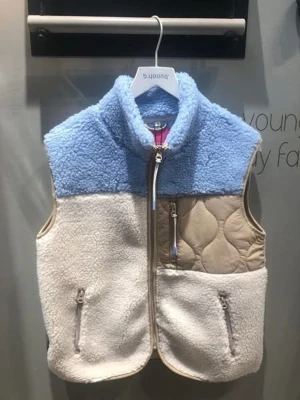 Färgglad teddyväst  - Mysig teddyväst i blått, beige och vitt. Västen har hög krage, dragkedja framtill och två fickor med dragkedja. Framsidan har quiltade detaljer i beige och resten är i fluffigt teddy-material. Perfekt för lager-på-lager-stil.