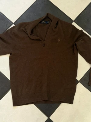 Brun tröja från Polo Ralph Lauren - Brun stickad tröja från Polo Ralph Lauren med halv dragkedja, materialet är i Kaschmir.