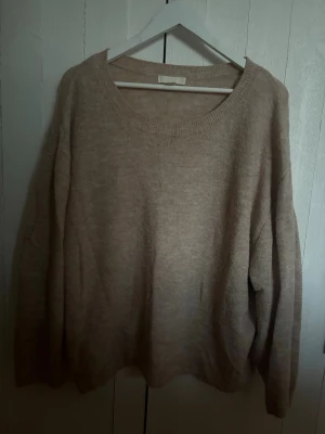 Beige stickad tröja från H&M - Mysig beige stickad tröja från H&M med rund halsringning och avslappnad passform. Tröjan har långa ärmar och är tillverkad i ett mjukt material som passar perfekt för kyligare dagar.
