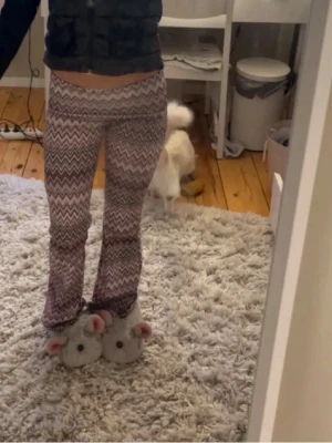 Mönstrade byxor  - Säljer ett par mjuka loungewear-byxor med zigzag-mönster i olika nyanser av rosa, lila och vitt. Byxorna har utsvängda ben och resår i midjan för extra komfort. Perfekta för att chilla hemma i och superbekväma!