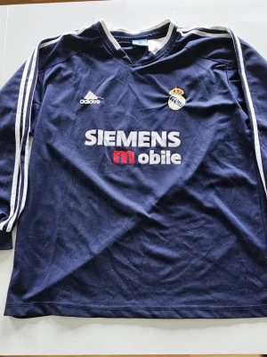 Real Madrid långärmad tröja Adidas - Säljer en ikonisk långärmad bortatröja från Real Madrids ”Galácticos”-era (säsongen 2003–2004). En riktig samlarobjekt för fotbollsfans! 