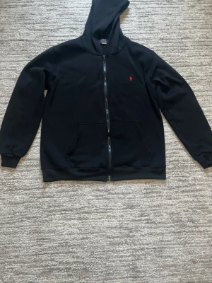 Svart hoodie med en röd häst på hoodien. - Svart hoodie med en dragkedja och en röd häst på. Den är lite använd fast en billig pris för en sån snygg hoodie. Den är skön att ha på sig bara att den tar upp damm väldigt lätt så var försiktig med det.