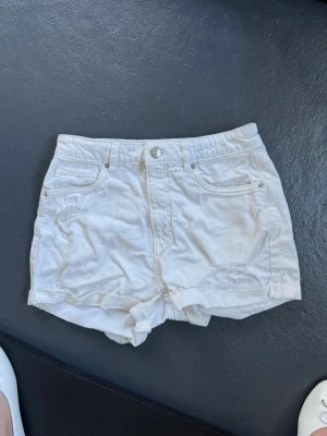 Vita denimshorts från LAB Industries - Snygga vita denimshorts från LAB Industries med hög midja och klassisk femficksdesign. Shortsen har råa kanter och diskreta slitningar framtill för en trendig look. Perfekta för sommaren och lätta att matcha med olika toppar.