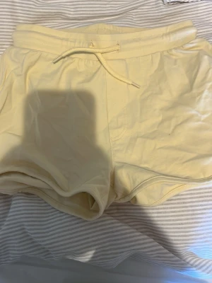 Gula shorts med snörning från Warp - Mjuka och bekväma ljusgula shorts från Warp med elastisk midja och snörning framtill. Perfekta för varma dagar och chill hemma. Tillverkade i bomull för en skön känsla.