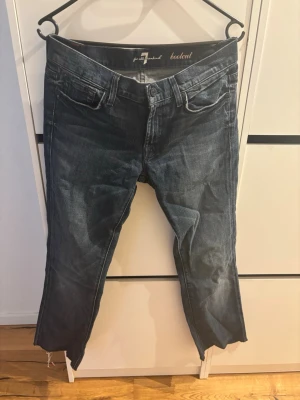Bootcut jeans från 7 For All Mankind - Mörkblå bootcut jeans från 7 For All Mankind med klassisk femficksdesign och snygga slitningar. Jeansen har låg midja och är tillverkade i denim med lätt stretch för skön passform. Perfekta för en avslappnad och trendig look.