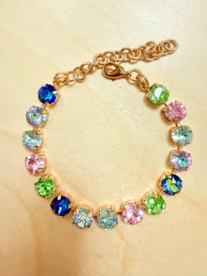 Armband med färgglada stenar - Ett armband med 8 mm stora, runda stenar  i olika färger som blått, grönt, rosa. Armbandet har guldfärgad kedja och justerbart lås. Perfekt för dig som gillar färg och vill sticka ut med dina accessoarer. Passar fint att kombinera med andra smycken tex från Svedbom (se näst sista bilden). Sista bilden är ett urval av färger som finns! 
