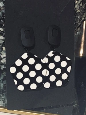 Svarta örhängen med vita prickar  - Örhängen med länkar i akryl som är svarta med vita prickar och rektangel formade örhängen . Längd 7cm 