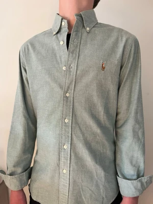 Grön skjorta från Ralph Lauren - Säljer denna klassiska gröna skjorta från Ralph Lauren med button-down krage och broderad logga på bröstet. Perfekt för varmare tider och tvärfet verkligen. Skickas snabbt och hör av er vid minsta fundering!!