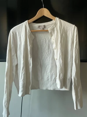 Vit kofta  - En klassisk vit kofta med rund halsringning och knäppning framtill. Långärmad modell i mjukt, tunt material med ribbade muddar vid ärmslut och nederkant. Perfekt att slänga över en t-shirt eller klänning. Liten i storlek. Super söt och har använts varsamt❣️