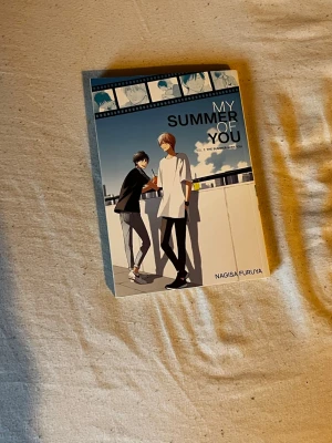 My Summer of You Vol 2 manga - Manga-bok 'My Summer of You Vol 2' av Nagisa Furuya. Omslaget har en illustration av två killar på ett tak i solnedgång, med blå och vita toner. Pocketformat, tryckt på papper. Perfekt för dig som gillar romantik och drama.