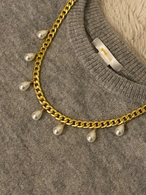 Guldfärgat halsband med pärldroppar - Snyggt halsband guldfärgad rostfritt stål med droppformade vita pärlor som hänger längs kedjan. Perfekt accessoar för att lyfta din outfit med en trendig och elegant touch. Lätt att matcha med olika stilar.