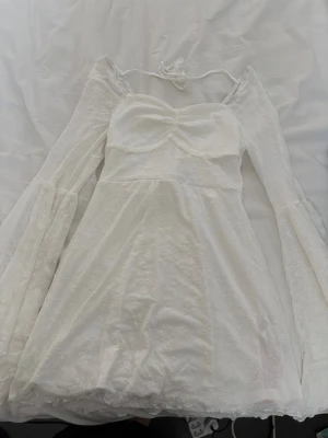 Vit kortklänning med vida ärmar - Supersöt vit kortklänning med långa, vida ärmar och snörning i ryggen🌸 Storlek M🌸 Klänningen är från shein och var tänkt som student klänning men hittade en annan så den är helt ny🌸Har för mig att den kostade runt 300kr🌸