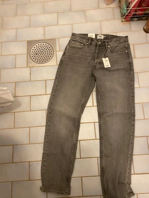 Grå high rise jeans från 157 - Säljer ett par grå jeans från 157, modell SEATTLE med high rise och relaxed fit. Jeansen har klassisk femficksdesign och raka ben. Perfekta för en avslappnad och trendig look. Materialet är denim i bomull.