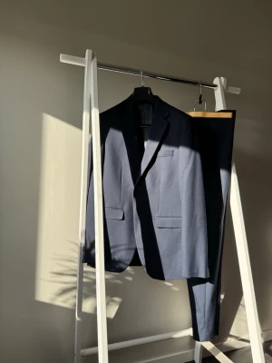 Mörkblå Slim Fit Riley kostym med kavaj och byxor  - Snygg mörkblå kostym från Riley som endast är använd vid ett tillfällen och helt fri från fläckar eller andra defekter. Kostym i ny skick med klassisk kavaj och matchande byxor. Kavajen har två fickor och enkelknäppning. Perfekt för dig som vill ha en stilren och tidlös look. NY PRIS PÅ BROTHERS HEMSIDA 2698kr!!!!