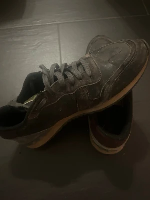 Svarta sneakers med vinröda detaljer - Snygga valentino garvani skor svart/grå med vinröda detaljer på hälen och beige sula. Skorna har klassisk snörning och är tillverkade i skinn och syntetmaterial. Perfekta för dig som gillar en stilren och sportig look.