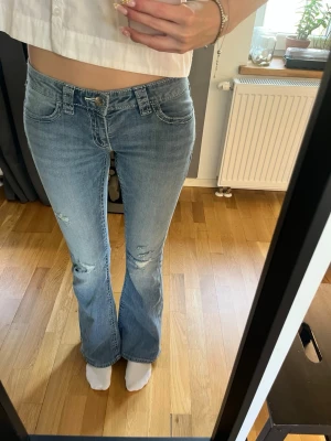 Gina Low waisted jeans med detaljer och hål - Lågmidjade jeans från Gina Tricot med hål i knäna och fina detaljer på bakfickorna. Köpta på Gina Young 14+ i storlek S så dem passar mig som är 171 cm. Jättebra skick, använt en gång. Hör av er för fler bilder eller frågor 🩷 