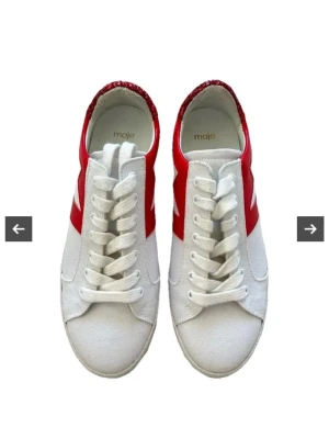 Vita sneakers med röd glitterdetalj - Snygga vita sneakers med röd blixtdetalj på sidan och glittrande röd häl. Skorna har vita snören och en klassisk låg modell. Perfekta för dig som vill sticka ut med lite extra glitter och färg i vardagen. Kartongen är kvar i de är endast använda en gång 