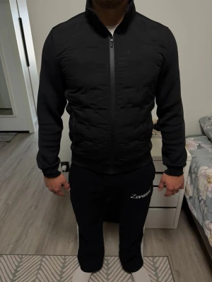 Svart Lindbergh Hybrid jacka  - Storlek M, höger arm längst ner har två hål (se sista bilden) annars bra skick, lite missfärgning som går att lösa säkert med medel. Hybrid jacka perfekt för våren.  Köpt för ca 1500kr. Säljer för 300kr.  Inget kvitto.