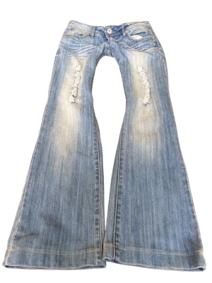  Vintage superlågmidjade bootcut jeans med slitningar - Såå sjukt snygga superlågmidjade vintage ljusblå bootcut jeans med slitna detaljer framtill. 