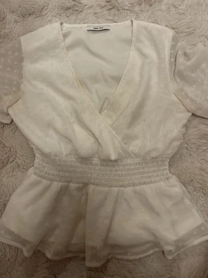 Jättesöt vit topp - Säljer den här vita toppen från About you som är använd några gånger därav sminkfläken på kanten. Det går inte bort i tvätten så där av billiga priset. Den är väl använd av rätt anledning då den är super fin. 
