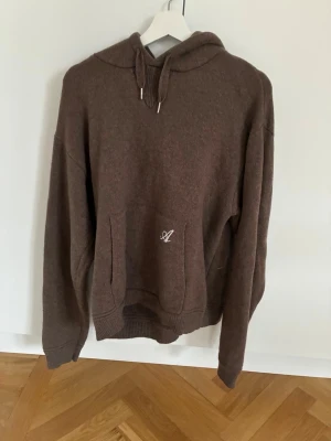 Brun hoodie från Axel Arigato - Brun hoodie från Axel Arigato med broderad logga på fickan och text på ryggen. I stickat skönt material, i bra skick 