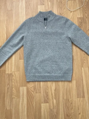 Grå halvzip tröja  - Snygg grå stickad tröja med halvzip och hög krage. Perfekt för lager på lager och enkel att matcha med olika outfits.