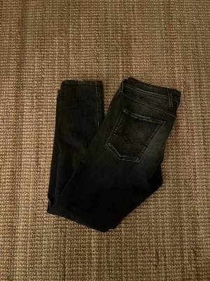 Svarta slim fit jeans från Replay - Säljer ett par svarta slim fit jeans från Replay med snygga slitningar och tvättade detaljer. Jeansen har klassisk femficksdesign, normalhög midja och smal passform. Perfekta för dig som gillar en modern och stilren look.🙌