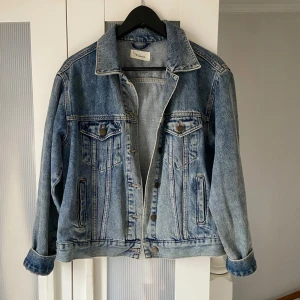 Blå jeansjacka från Twintip - Säljer en klassisk blå jeansjacka från Twintip. Jackan har en oversize passform med knappar framtill. Perfekt för en avslappnad stil.