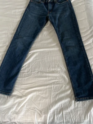 Mörkblå raka jeans från Levi's - Klassiska mörkblå jeans från Levi's med rak passform och fem fickor. Jeansen har en tidlös look med subtila slitningar och är tillverkade i denim. Perfekta för dig som gillar en enkel och stilren stil.