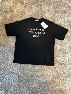 Acne Studios Stockholm 1996 Tee – S  - Svart T-shirt från Acne Studios i storlek S. Oversized fit – sitter riktigt clean 🔥               Helt ny med tags (aldrig använd)                               Sjukt snygg basic som passar till allt                                 Nypris ca 1200–1500 kr 💰                                                         Pris: 799 kr Kan sänka vid snabb affär