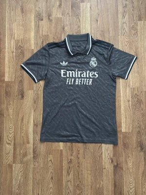 Real Madrid Third kit  24/25 Grå  - Real Madrid tredjeställ från säsongen 24/25 storlek M sitter som M. Använd ett antal gånger men inga synliga defekter. Säljer eftersom jag inte tycker om den supermycket så använder den aldrig. 