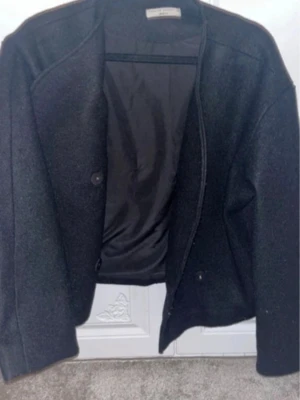 Svart kappa - Stilren Klassisk rak modell med diskreta knappar och helfodrad insida. Perfekt för dig som gillar minimalistisk och tidlös design. Enkel att matcha med olika outfits.