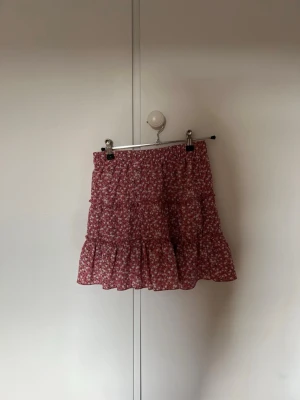 Rosa blommig volangkjol från Zara med shorts - Supersöt rosa kjol från Zara med små vita och rosa blommor. Kjolen har volanger och resår i midjan för en bekväm passform. Perfekt för dig som gillar en feminin och trendig stil. Lätt och luftig, passar till många olika outfits. Str 164 cm och har shorts